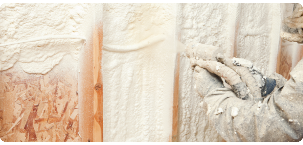 Builder spraying foam on a wall to seal it
