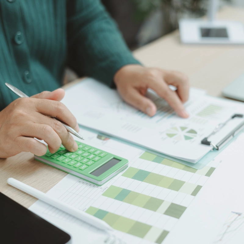 Person calculating energy savings with green calculator and efficiency charts